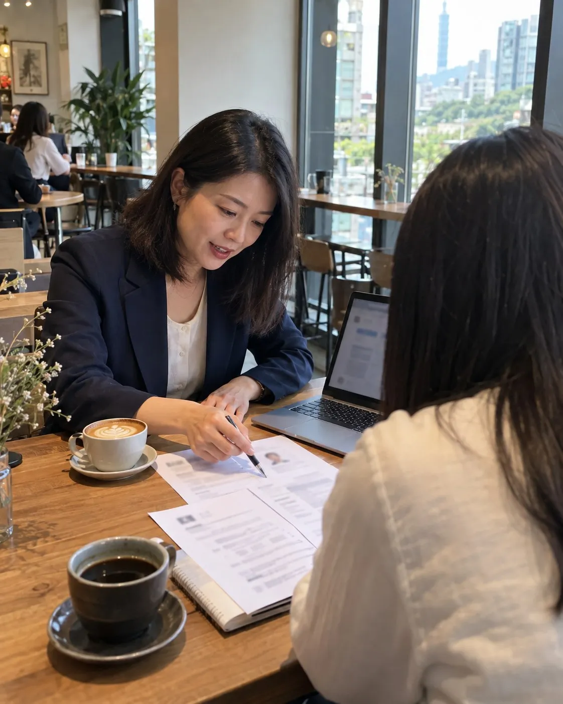 沈予安在咖啡店的木桌前,拿筆在印出來的履歷上寫建議,對面坐著學員,桌上有筆電和咖啡